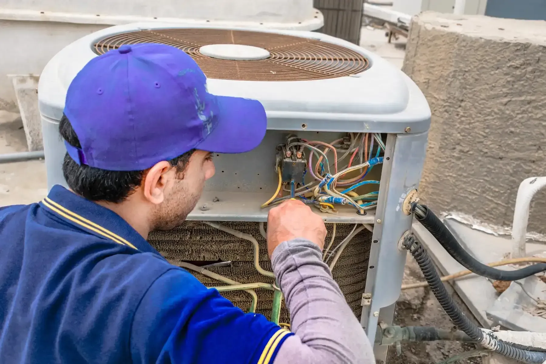 AC technician servicing and tuning up an outdoor air conditioning unit.